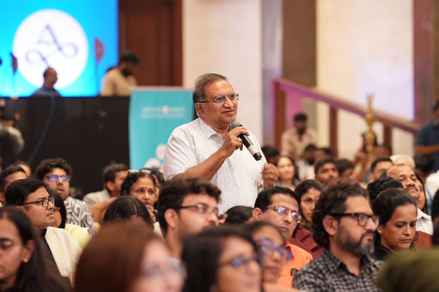 A senior business leader standing in the audience asking a question on the mic